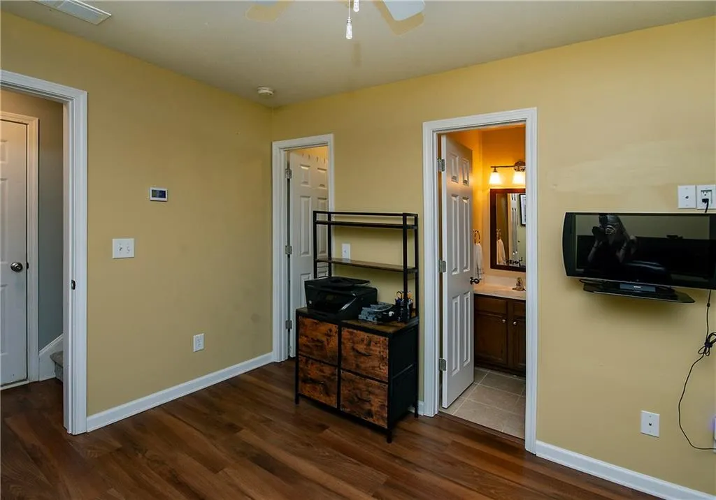 Bedroom featuring dark wood-style floors, a ceiling fan, and ensuite bathroom
