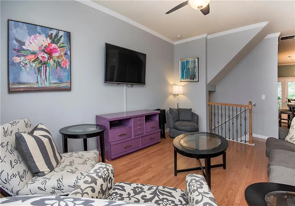 Living area featuring crown molding, wood finished floors, and a ceiling fan