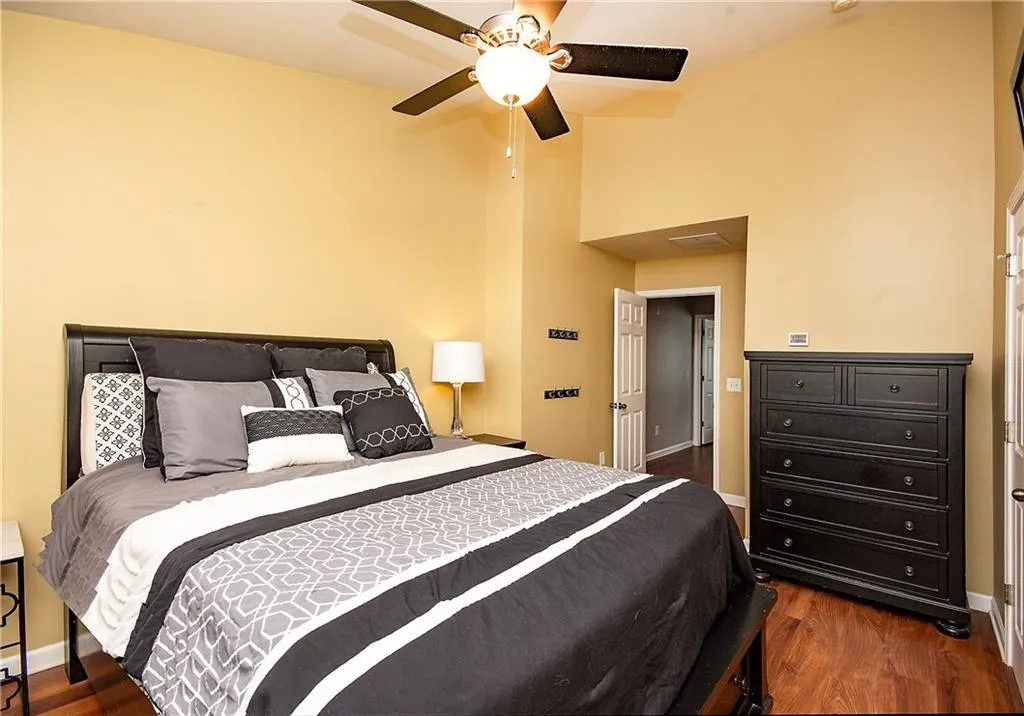 Bedroom with dark wood-style floors, a ceiling fan, and a high ceiling