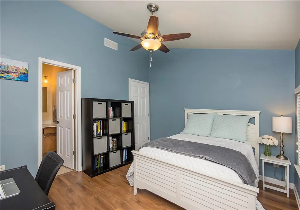 Bedroom with lofted ceiling, dark wood-type flooring, a ceiling fan, a desk, and ensuite bathroom