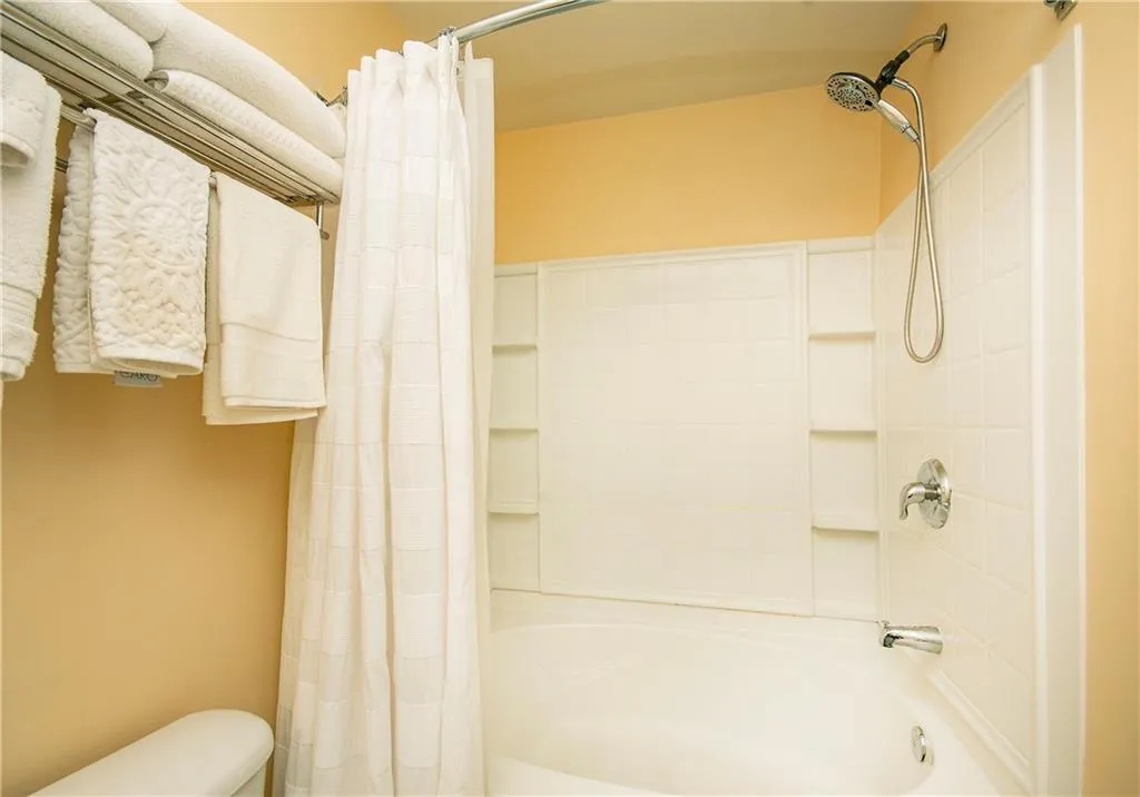 Bathroom featuring shower / bathtub combination with curtain and toilet