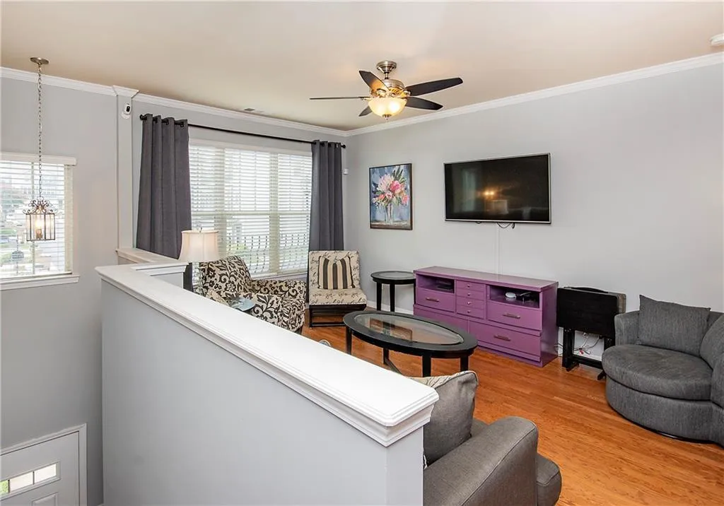 Living area with healthy amount of natural light, crown molding, light wood-style flooring, and a chandelier