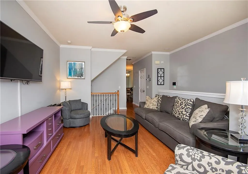 Living area featuring ornamental molding, light wood finished floors, and ceiling fan