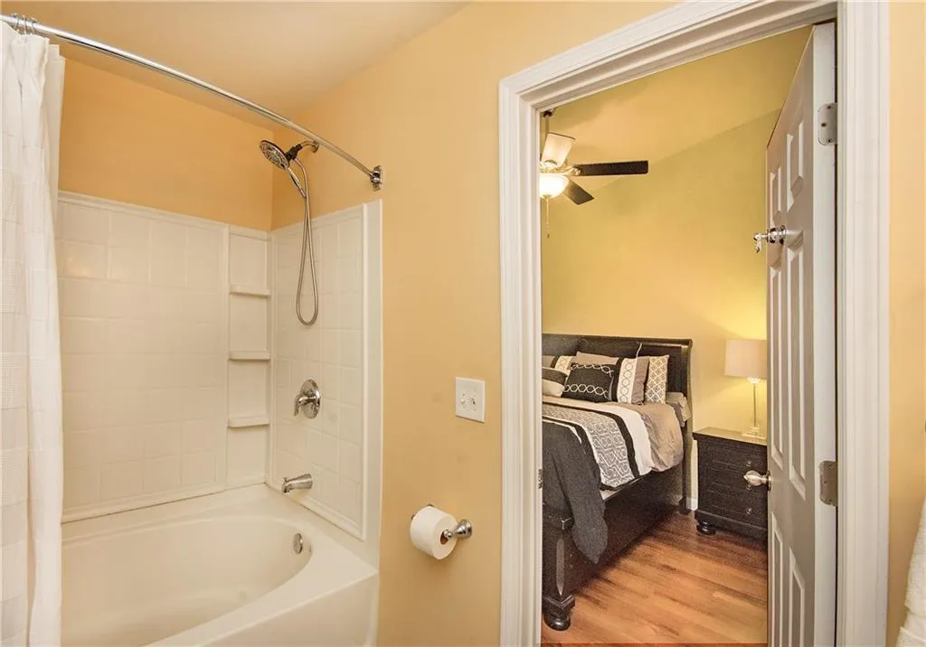 Ensuite bathroom featuring shower / tub combo, wood finished floors, and a ceiling fan