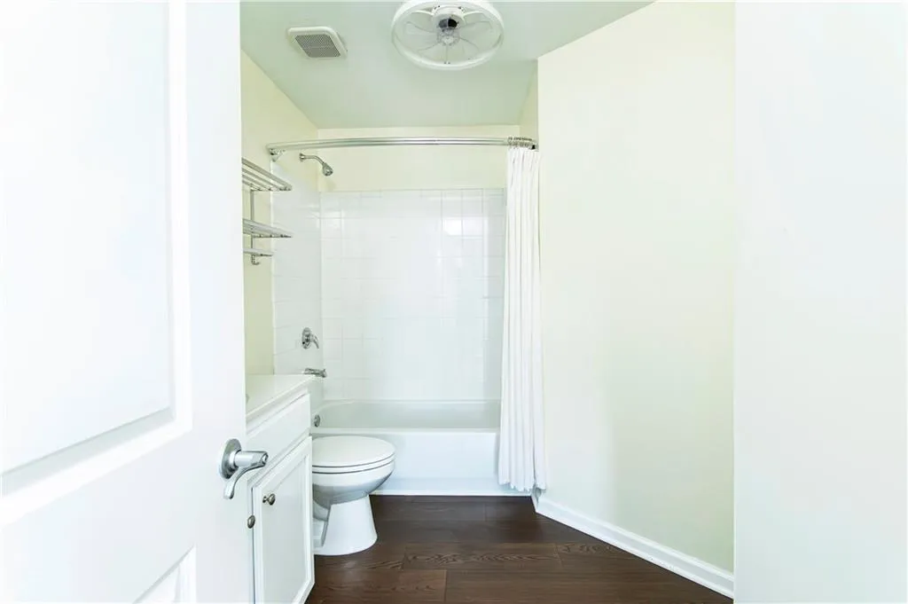 Full bath with shower / bathtub combination with curtain, dark wood-style flooring, and vanity