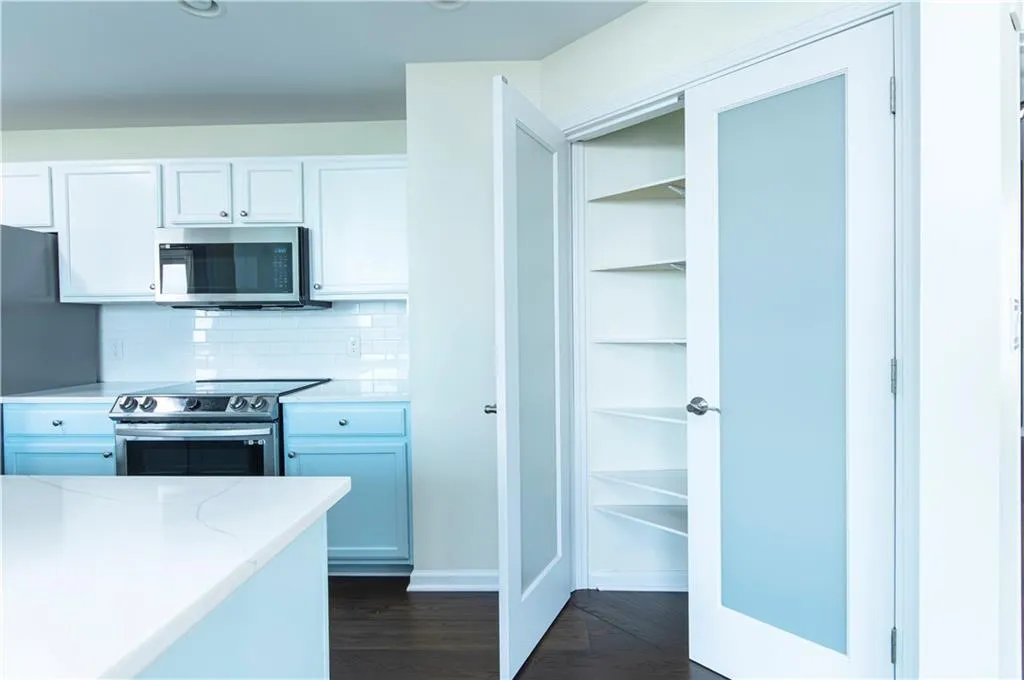Kitchen with white cabinetry, stainless steel appliances, tasteful backsplash, dark wood finished floors, and recessed lighting