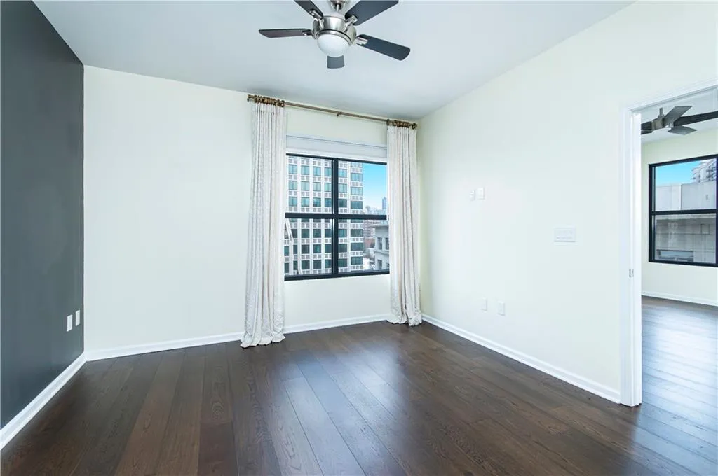Empty room featuring ceiling fan and dark wood-style floors