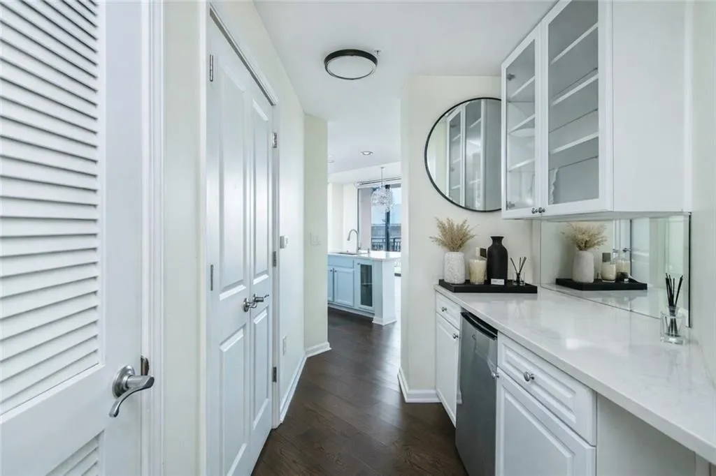Bar area with glass insert cabinets, light stone countertops, white cabinetry, and dark wood finished floors