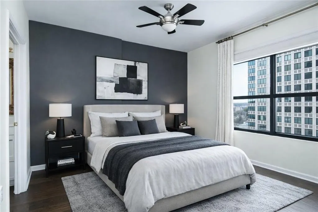 Bedroom featuring dark wood finished floors, ceiling fan, a view of city, and an accent wall
