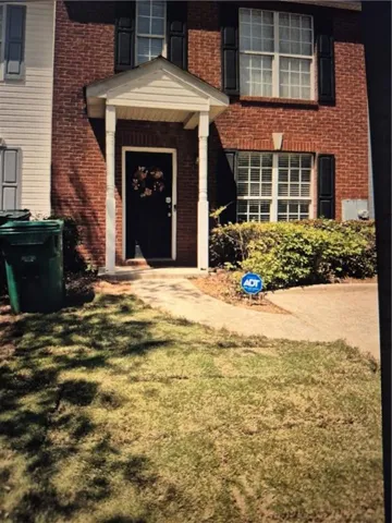 Entrance to property featuring brick siding and a lawn