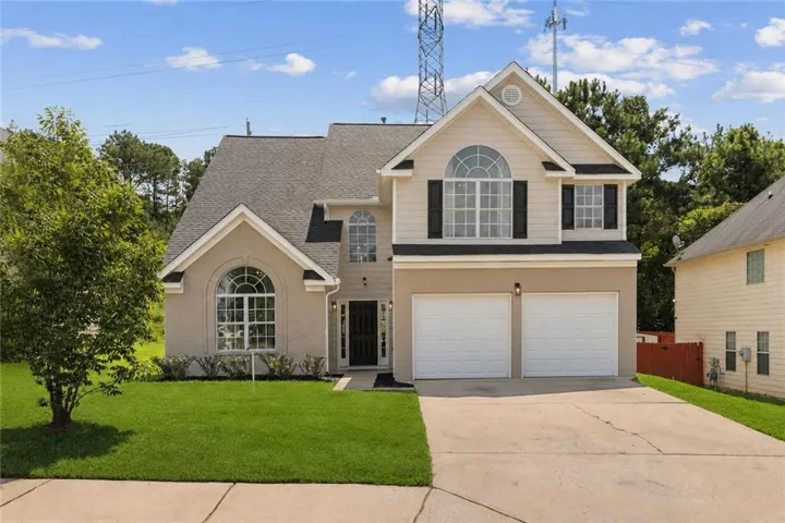 Two-story exterior with a two-car garage, arched windows, and a concrete driveway