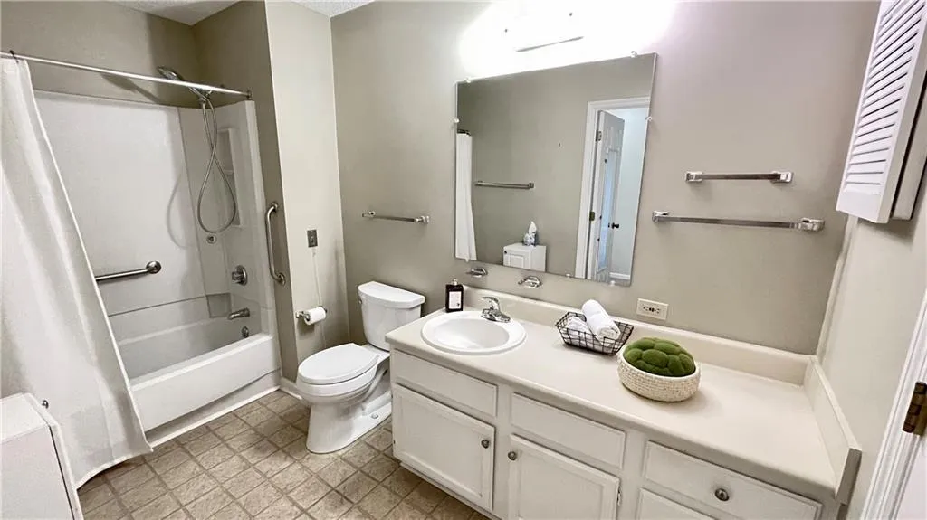 Full bathroom featuring vanity, shower / bath combination with curtain, and toilet