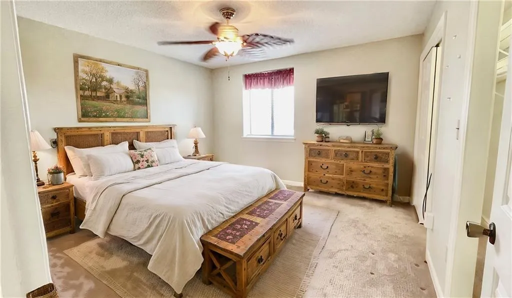 Carpeted bedroom featuring ceiling fan, a textured ceiling, and a closet