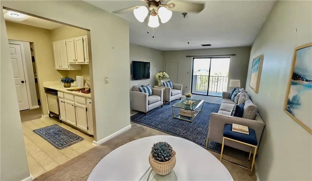 Living room featuring light carpet, ceiling fan, and sink