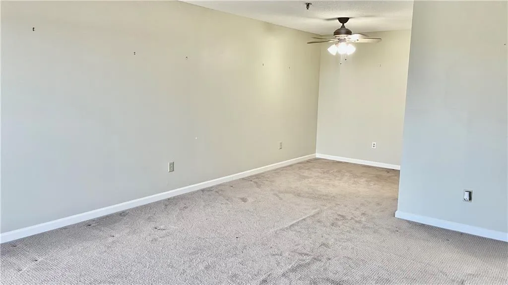 Carpeted empty room featuring a textured ceiling and ceiling fan
