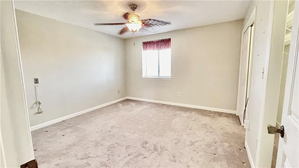 Unfurnished bedroom featuring light carpet, a textured ceiling, and ceiling fan