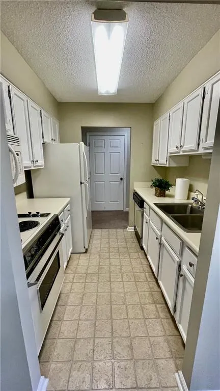 Kitchen with white cabinetry, sink, a textured ceiling, and range