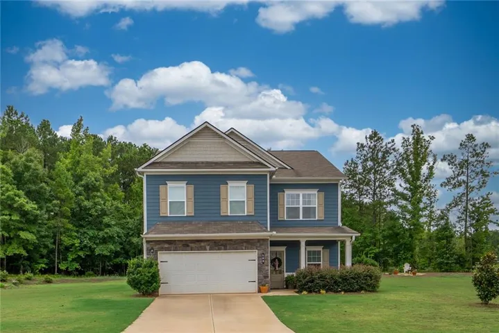 Two-story residence featuring blue siding, a stone facade accent, and a front-facing garage
