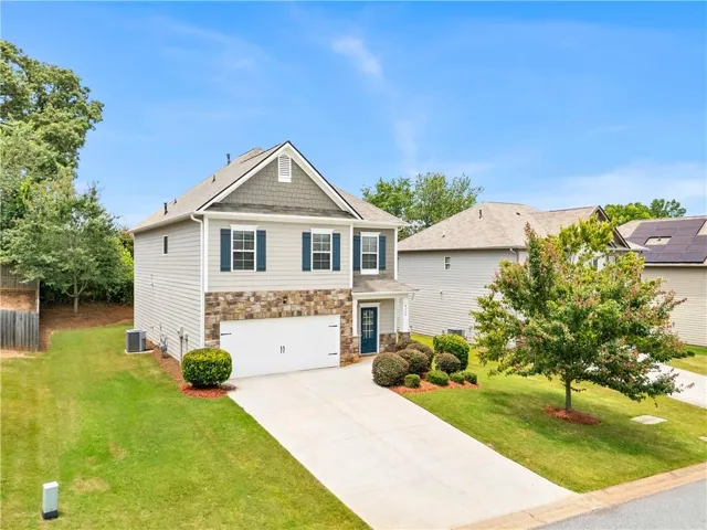 Two-story residence featuring a combination siding and stone facade, an attached two-car garage, and a concrete driveway