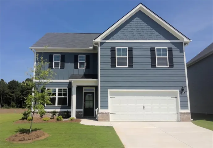 Two-story residence featuring a two-car garage, dark-paneled door, and a combination of horizontal siding, vertical board and batten siding, and shake siding