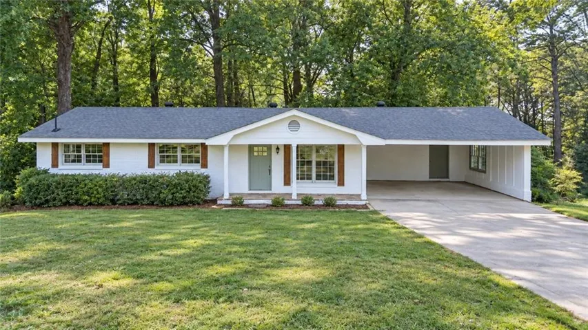 Single-story residence featuring a white exterior, dark shingle roof, and a covered carport