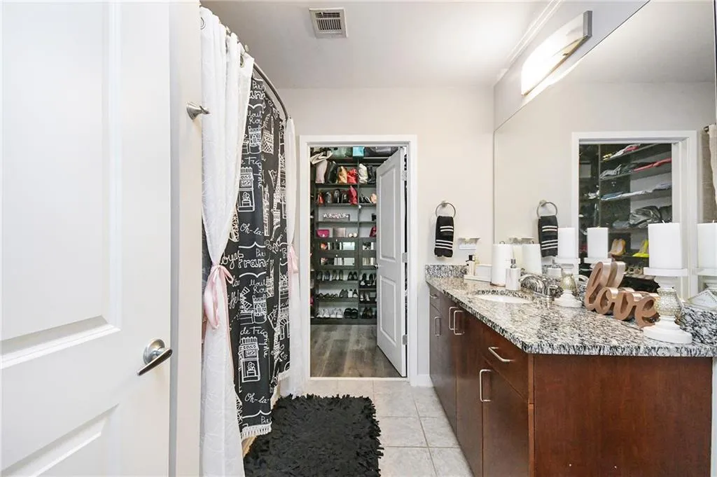 Full bath featuring vanity, tile patterned flooring, and a spacious closet