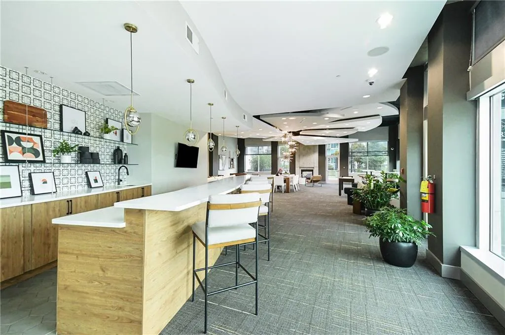 Bar with hanging light fixtures, dark colored carpet, oven, and recessed lighting