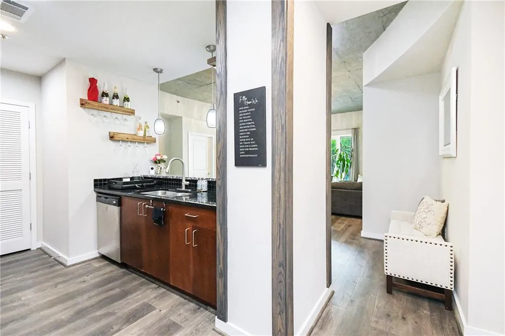 Bar featuring stainless steel dishwasher and light wood-type flooring