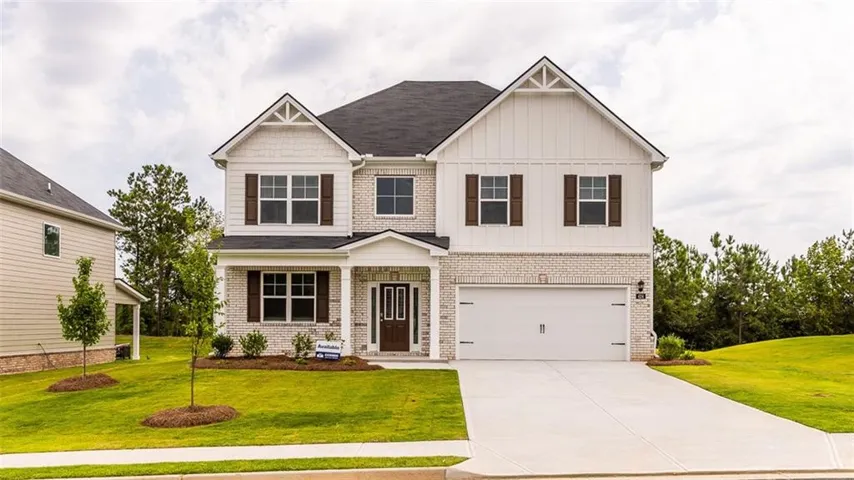 Two-story residential exterior featuring brick and vertical siding, a covered entry, an attached two-car garage, and a concrete driveway