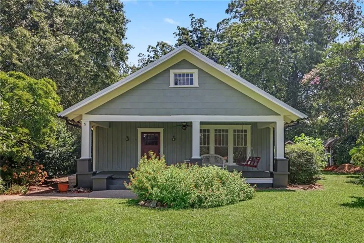 Gable roofline, covered front porch, vertical siding, central entrance door, multi-pane windows
