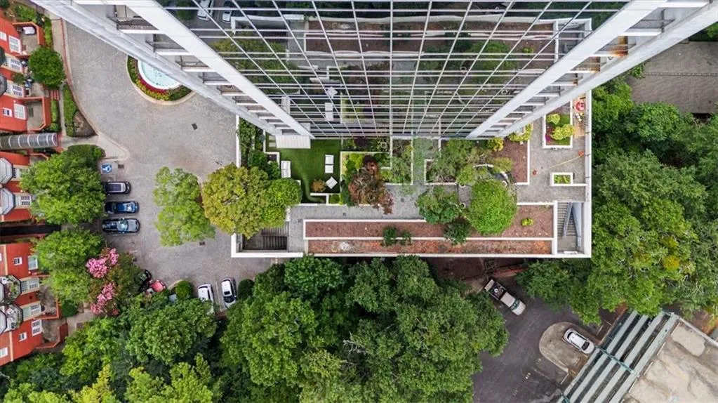 Modern high-rise residential building featuring a rooftop terrace with artificial turf, mature plantings, and outdoor seating areas