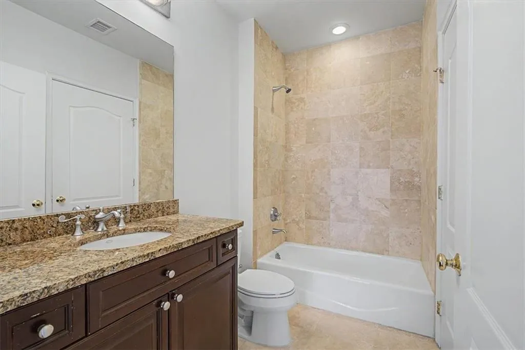 Bathroom featuring a dark wood-finish vanity with granite countertop, undermount sink, and polished chrome fixtures