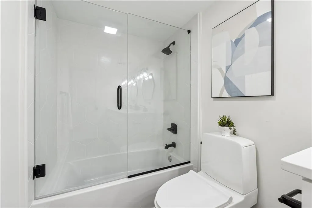 Full bathroom featuring bath / shower combo with glass door and toilet