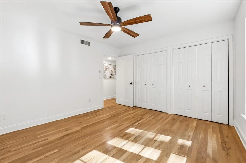 Unfurnished bedroom with two closets, light wood finished floors, and a ceiling fan