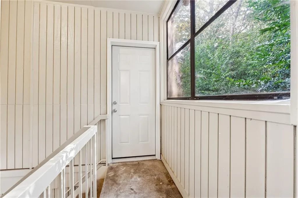 Doorway to outside with wood walls and unfinished concrete floors