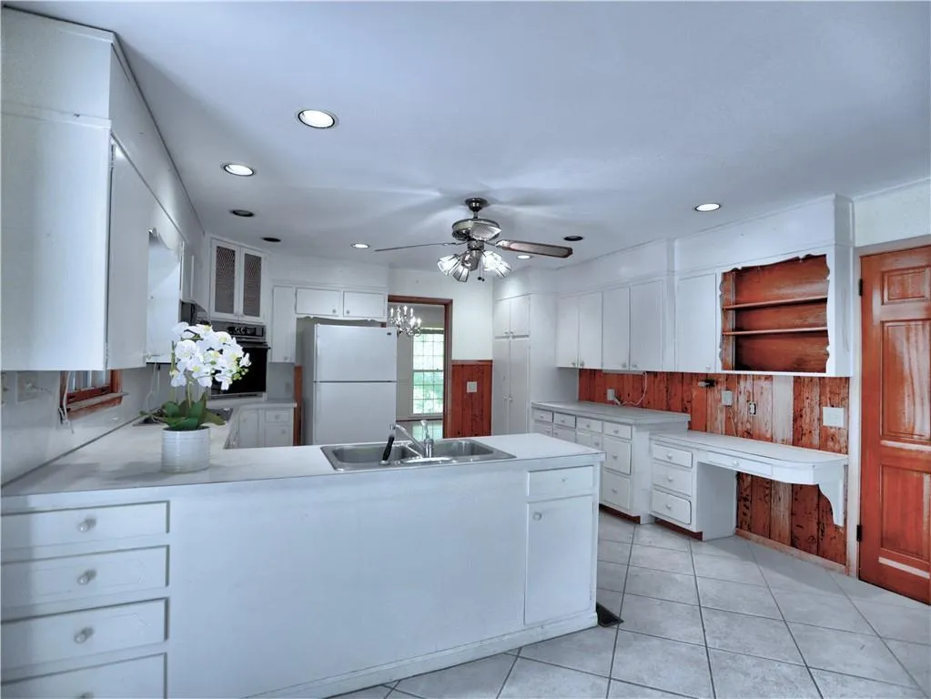 Kitchen featuring white cabinets, sink, white fridge, light tile flooring, and ceiling fan