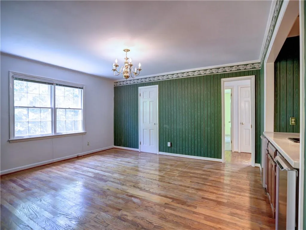 Unfurnished room with hardwood / wood-style flooring and an inviting chandelier