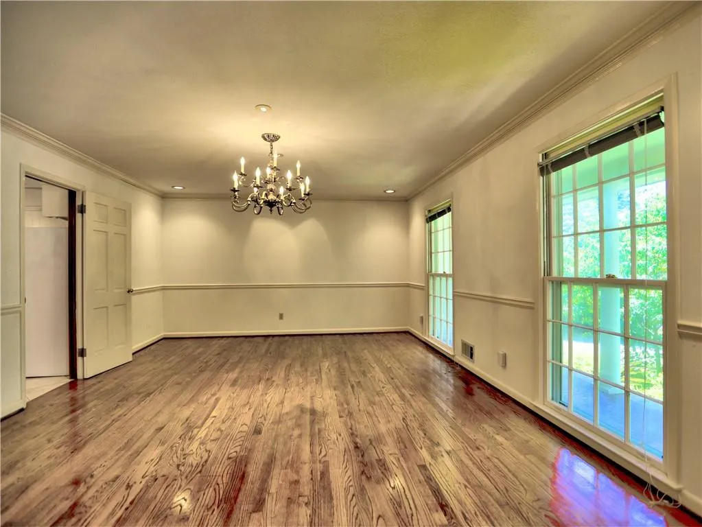 Unfurnished dining area featuring plenty of natural light, hardwood / wood-style flooring, and a chandelier