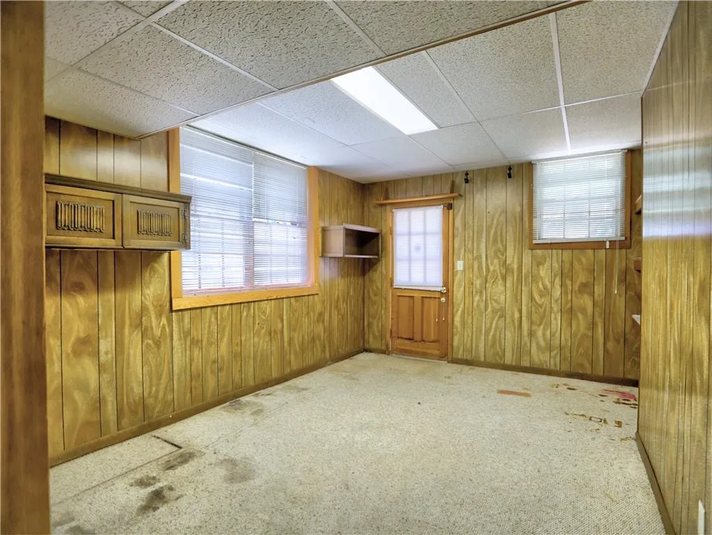 Unfurnished room with carpet floors, a paneled ceiling, and wood walls