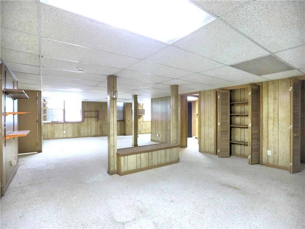 Basement featuring wood walls and a drop ceiling