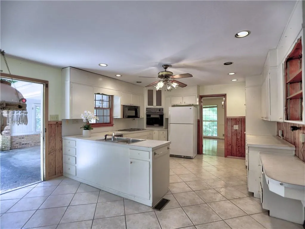 Kitchen with white cabinetry, sink, black appliances, and light tile floors