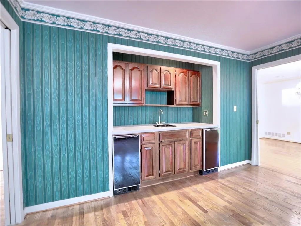 Kitchen with wine cooler, light hardwood / wood-style floors, crown molding, dishwasher, and sink