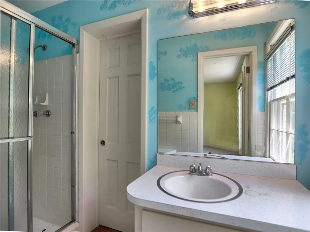 Bathroom featuring a shower with shower door and vanity