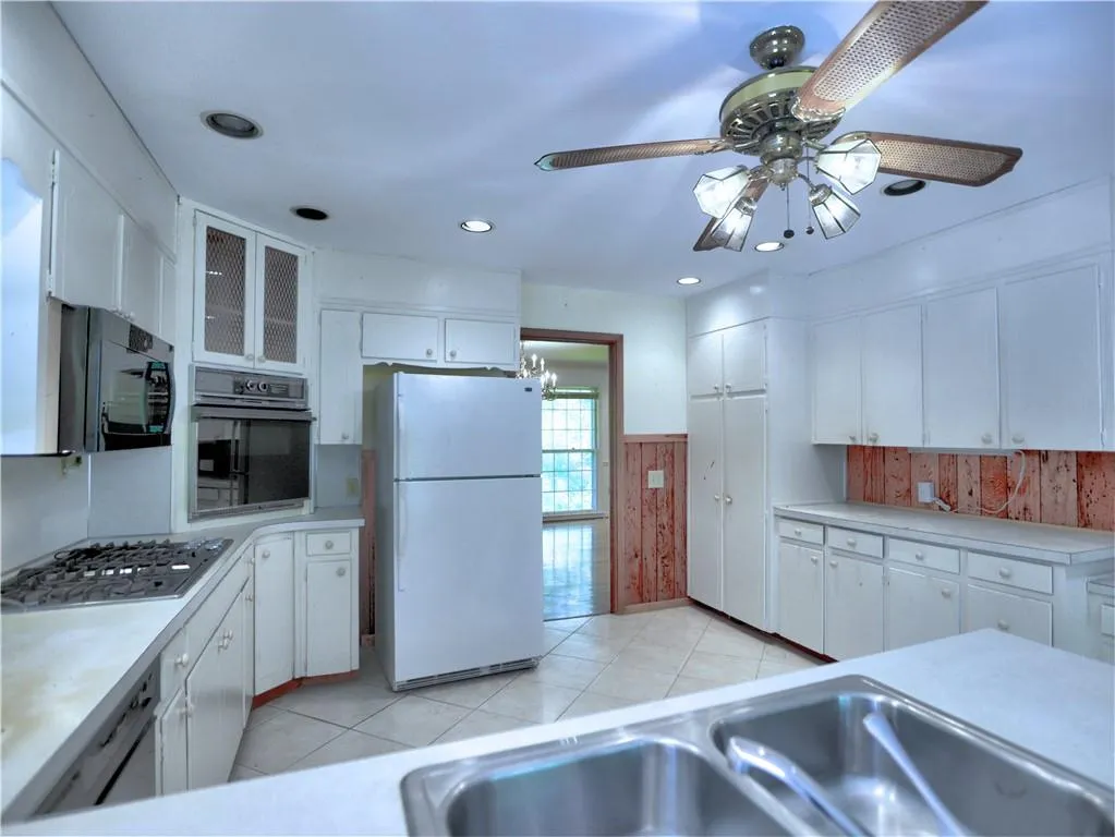 Kitchen featuring stainless steel appliances, white cabinets, ceiling fan, and light tile floors