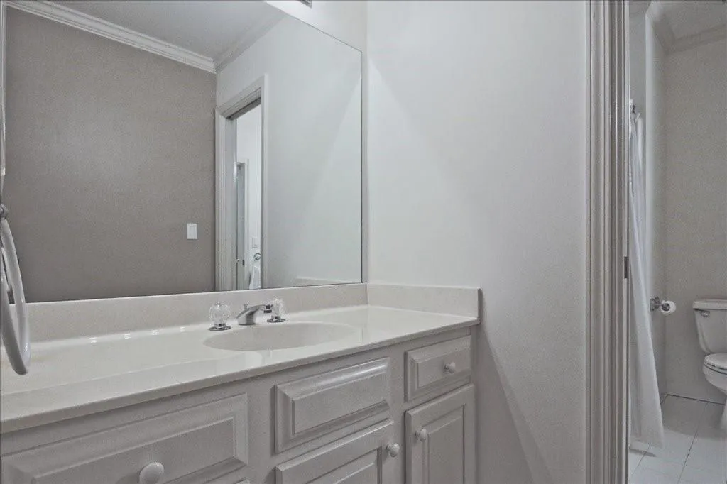 Bathroom with crown molding, vanity, and light tile patterned flooring