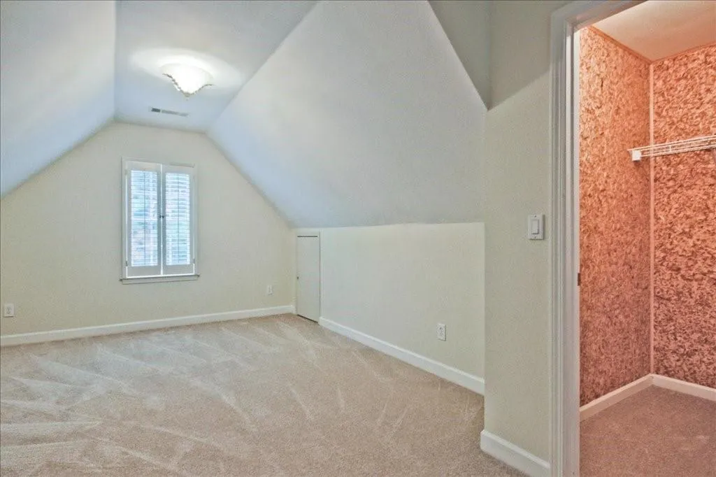 Additional living space with vaulted ceiling and light colored carpet