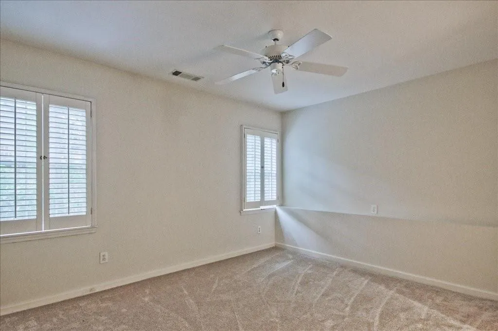 Empty room with carpet floors and ceiling fan
