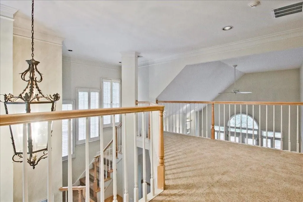 Hall featuring healthy amount of natural light, crown molding, and carpet