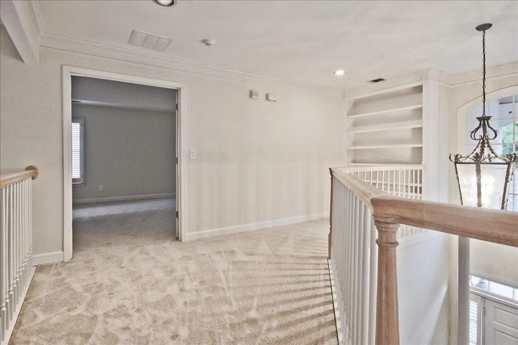 Hallway featuring an upstairs landing, carpet flooring, crown molding, built in features, and recessed lighting