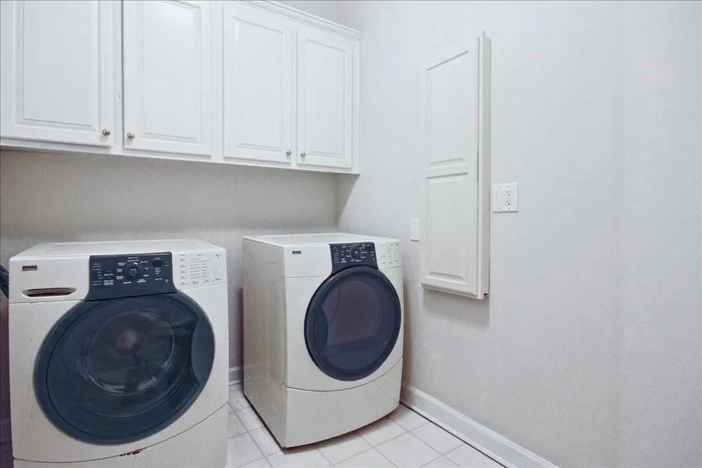 Laundry room featuring light tile patterned floors, washer and dryer, and cabinet space
